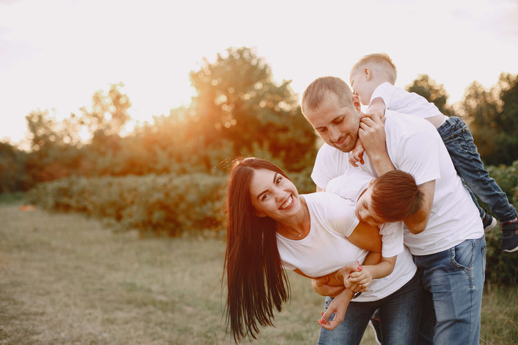 Happy Family of four in a park with trees and sunlight
